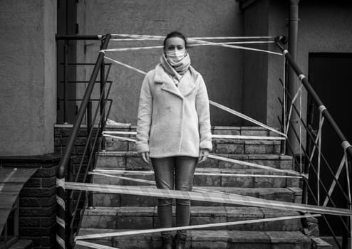 Photo of a girl in a mask. Standing on the street with danger warning tapes. isolated Covid-19 pandemic.