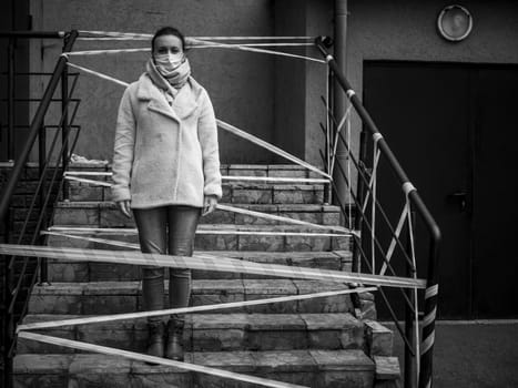 Photo of a girl in a mask. Standing on the street with danger warning tapes. isolated Covid-19 pandemic.