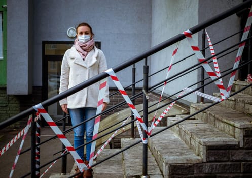 Photo of a girl in a mask. Standing on the street with danger warning tapes. isolated Covid-19 pandemic.