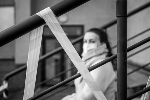 Photo of a girl in a mask. Sitting on the street with danger warning tapes. isolated Covid-19 pandemic.