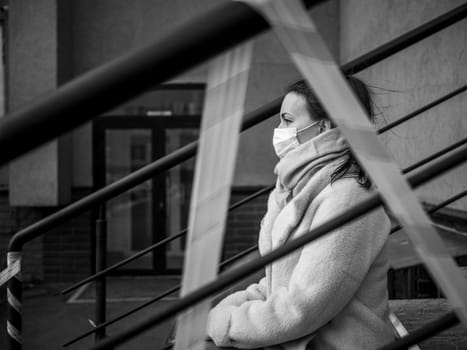 Photo of a girl in a mask. Sitting on the street with danger warning tapes. isolated Covid-19 pandemic.