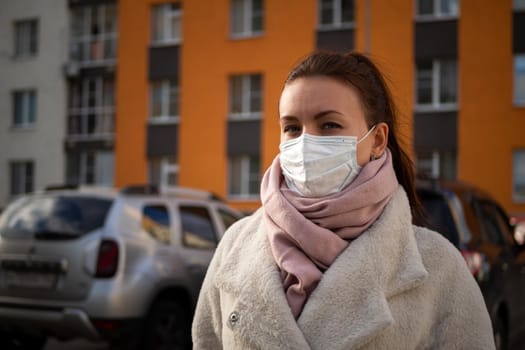 Shot of a girl in wearing face mask for protection, on the street. Against the background of a residential building with windows. lockdown Covid-19 pandemic.