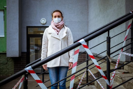 Photo of a girl in a mask. Standing on the street with danger warning tapes. isolated Covid-19 pandemic.