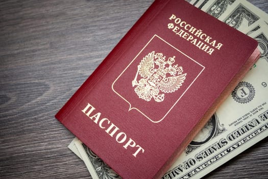 A foreign passport and dollars on a wooden background. Photos of documents and banknotes.