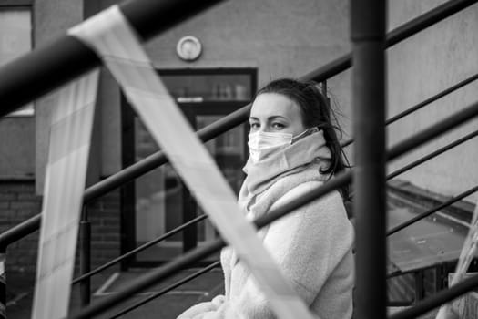 Photo of a girl in a mask. Sitting on the street with danger warning tapes. isolated Covid-19 pandemic.