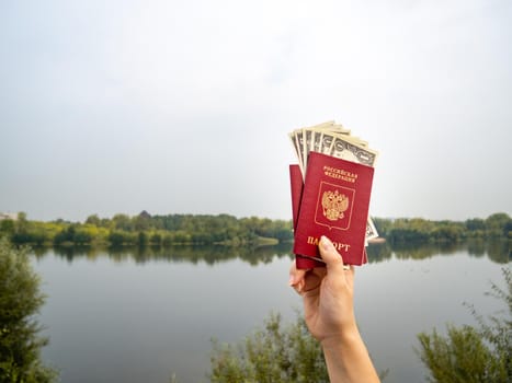 A foreign passport and dollars in your hand, against the background of nature. Filmed outdoors.