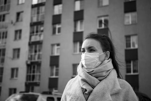 Shot of a girl in wearing face mask for protection, on the street. Against the background of a residential building with windows. lockdown Covid-19 pandemic.