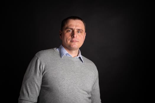 handsome businessman in a suit looks at the camera. isolated on a black background