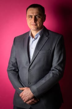 handsome businessman in a suit looks at the camera. isolated on a pink background