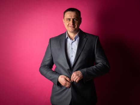 handsome businessman in a suit looks at the camera. isolated on a pink background