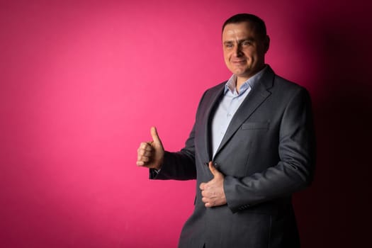 handsome businessman in a suit looks at the camera. isolated on a pink background