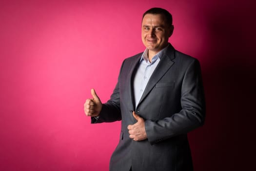 handsome businessman in a suit looks at the camera. isolated on a pink background