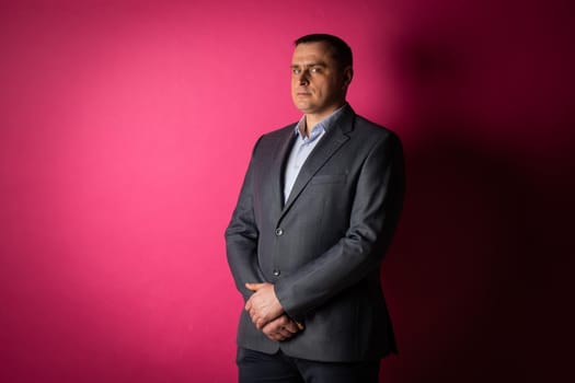 handsome businessman in a suit looks at the camera. isolated on a pink background