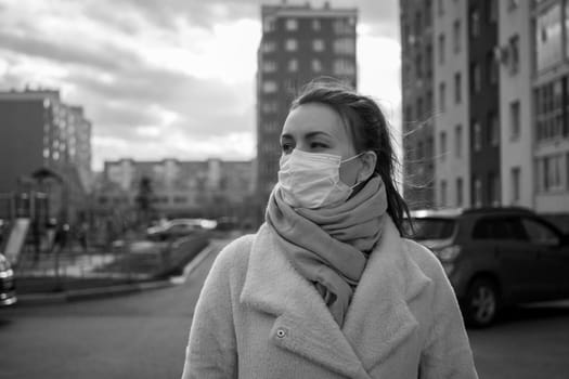 Shot of a girl in wearing face mask for protection, on the street. Against the background of a residential building with windows. lockdown Covid-19 pandemic.