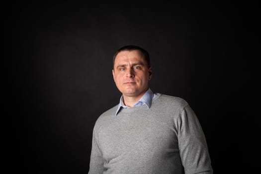 handsome businessman in a suit looks at the camera. isolated on a black background