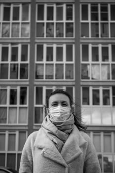 Shot of a girl in wearing face mask for protection, on the street. Against the background of a residential building with windows. lockdown Covid-19 pandemic.