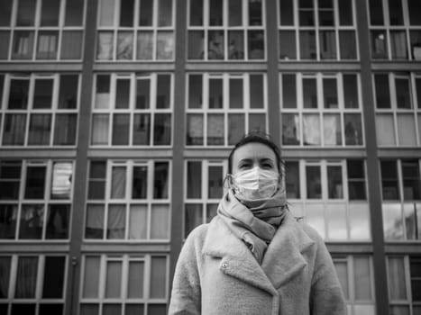 Shot of a girl in wearing face mask for protection, on the street. Against the background of a residential building with windows. lockdown Covid-19 pandemic.