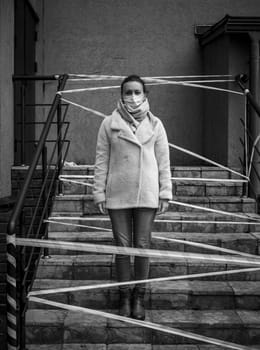 Photo of a girl in a mask. Standing on the street with danger warning tapes. isolated Covid-19 pandemic.