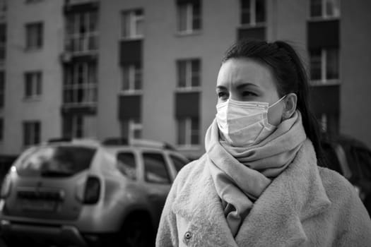 Shot of a girl in wearing face mask for protection, on the street. Against the background of a residential building with windows. lockdown Covid-19 pandemic.