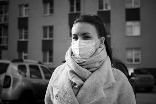 Shot of a girl in wearing face mask for protection, on the street. Against the background of a residential building with windows. lockdown Covid-19 pandemic.