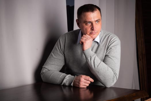 handsome man in a suit poses in an interior studio. looks at the camera