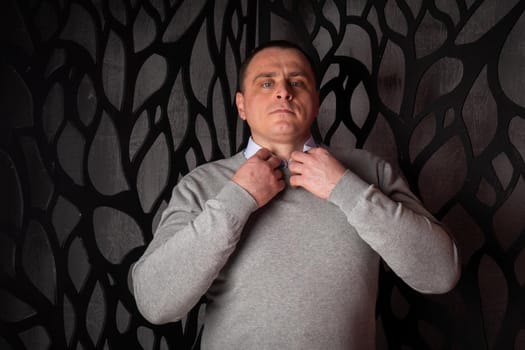 handsome man in a suit poses in an interior studio. looks at the camera