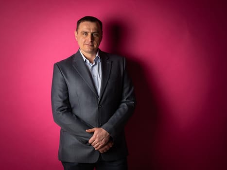 handsome businessman in a suit looks at the camera. isolated on a pink background