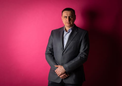 handsome businessman in a suit looks at the camera. isolated on a pink background