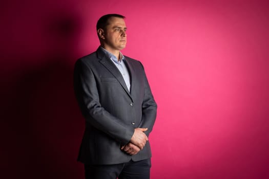 handsome businessman in a suit looks at the camera. isolated on a pink background