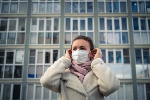 Shot of a girl in wearing face mask for protection, on the street. Against the background of a residential building with windows. lockdown Covid-19 pandemic.