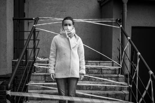 Photo of a girl in a mask. Standing on the street with danger warning tapes. isolated Covid-19 pandemic.