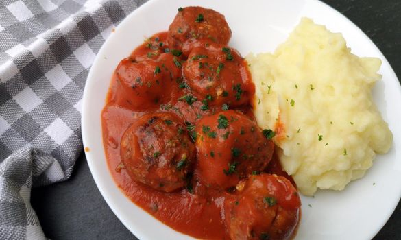 Delicious meatballs in tomato sauce with mashed potatoes, served on white plate