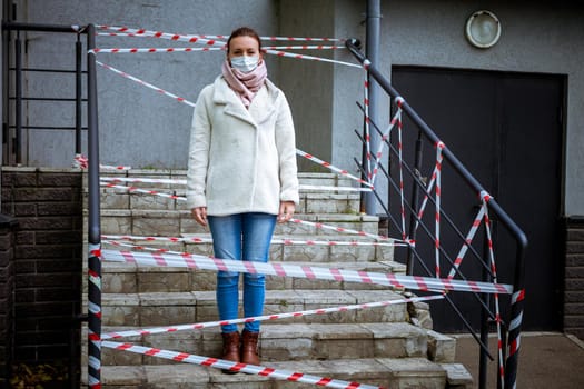 Photo of a girl in a mask. Standing on the street with danger warning tapes. isolated Covid-19 pandemic.