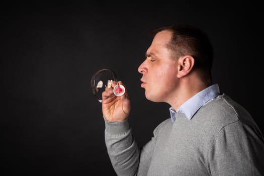 handsome man in a suit is blowing soap bubbles. isolated on a black background