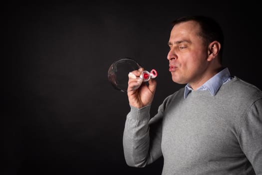 handsome man in a suit is blowing soap bubbles. isolated on a black background