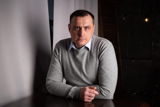 handsome man in a suit poses in an interior studio. looks at the camera