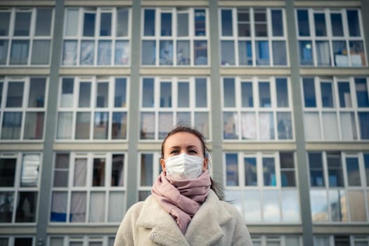 Shot of a girl in wearing face mask for protection, on the street. Against the background of a residential building with windows. lockdown Covid-19 pandemic.