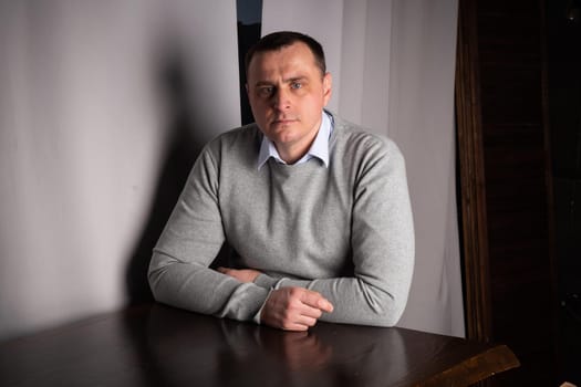 handsome man in a suit poses in an interior studio. looks at the camera