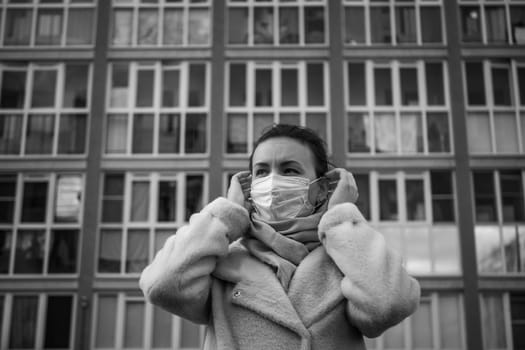 Shot of a girl in wearing face mask for protection, on the street. Against the background of a residential building with windows. lockdown Covid-19 pandemic.