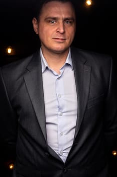 handsome businessman in a suit looks at the camera. isolated on a black background