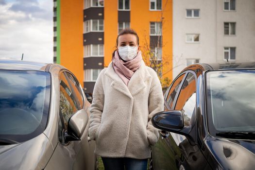 picture of a girl in a mask, on the street. Against the background of parked cars. isolated Covid-19 pandemic.