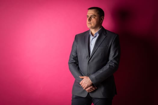 handsome businessman in a suit looks at the camera. isolated on a pink background