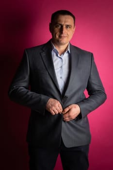 handsome businessman in a suit looks at the camera. isolated on a pink background