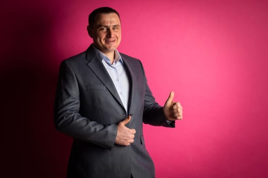 handsome businessman in a suit looks at the camera. isolated on a pink background