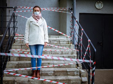 Photo of a girl in a mask. Standing on the street with danger warning tapes. isolated Covid-19 pandemic.