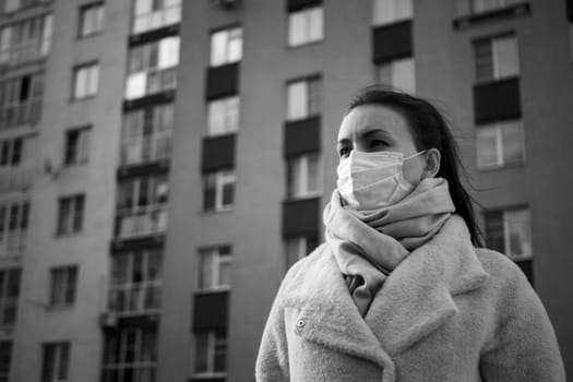 Shot of a girl in wearing face mask for protection, on the street. Against the background of a residential building with windows. lockdown Covid-19 pandemic.