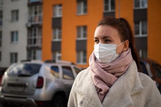 Shot of a girl in wearing face mask for protection, on the street. Against the background of a residential building with windows. lockdown Covid-19 pandemic.