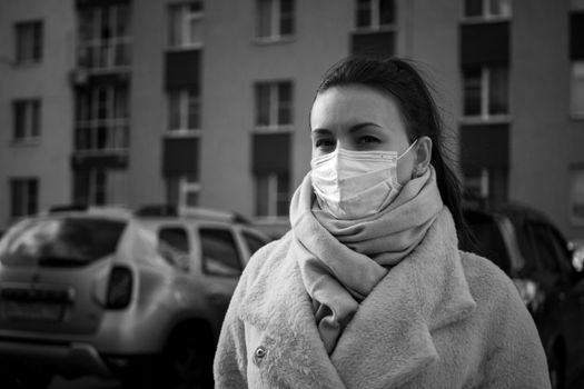 Shot of a girl in wearing face mask for protection, on the street. Against the background of a residential building with windows. lockdown Covid-19 pandemic.