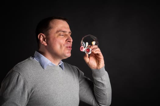 handsome man in a suit is blowing soap bubbles. isolated on a black background