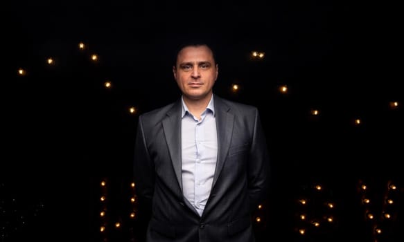 handsome businessman in a suit looks at the camera. isolated on a black background